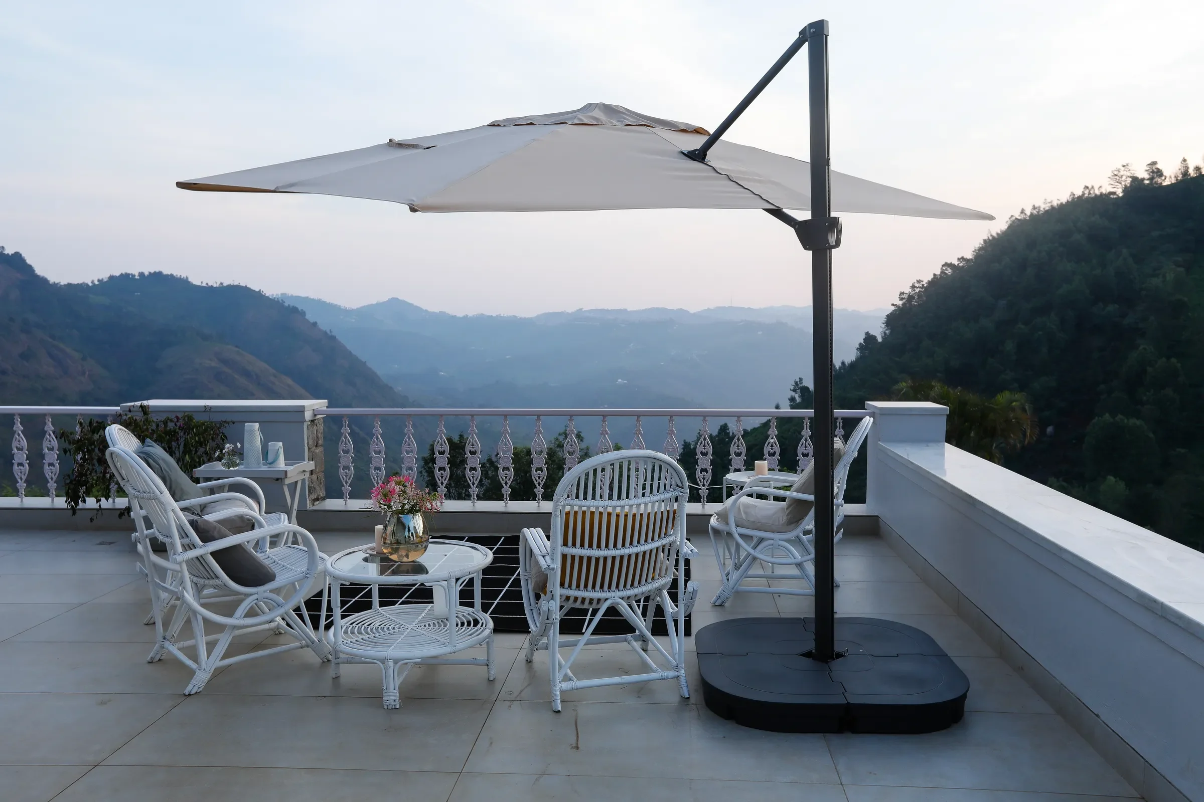 Terrace seating under a cantilevered umbrella, the Nilgiris beyond
