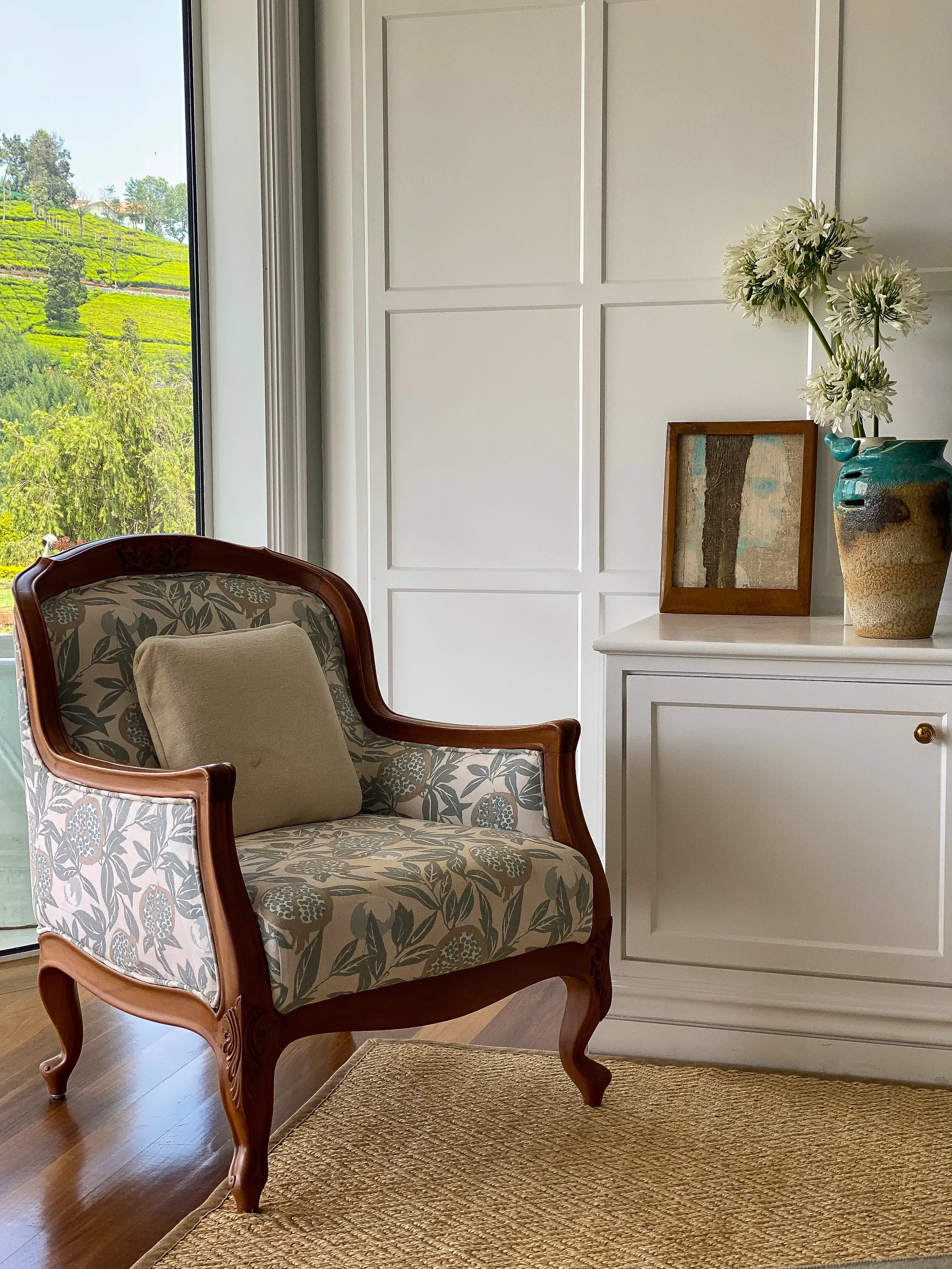 An antique armchair against panelled walls, tea gardens through the window