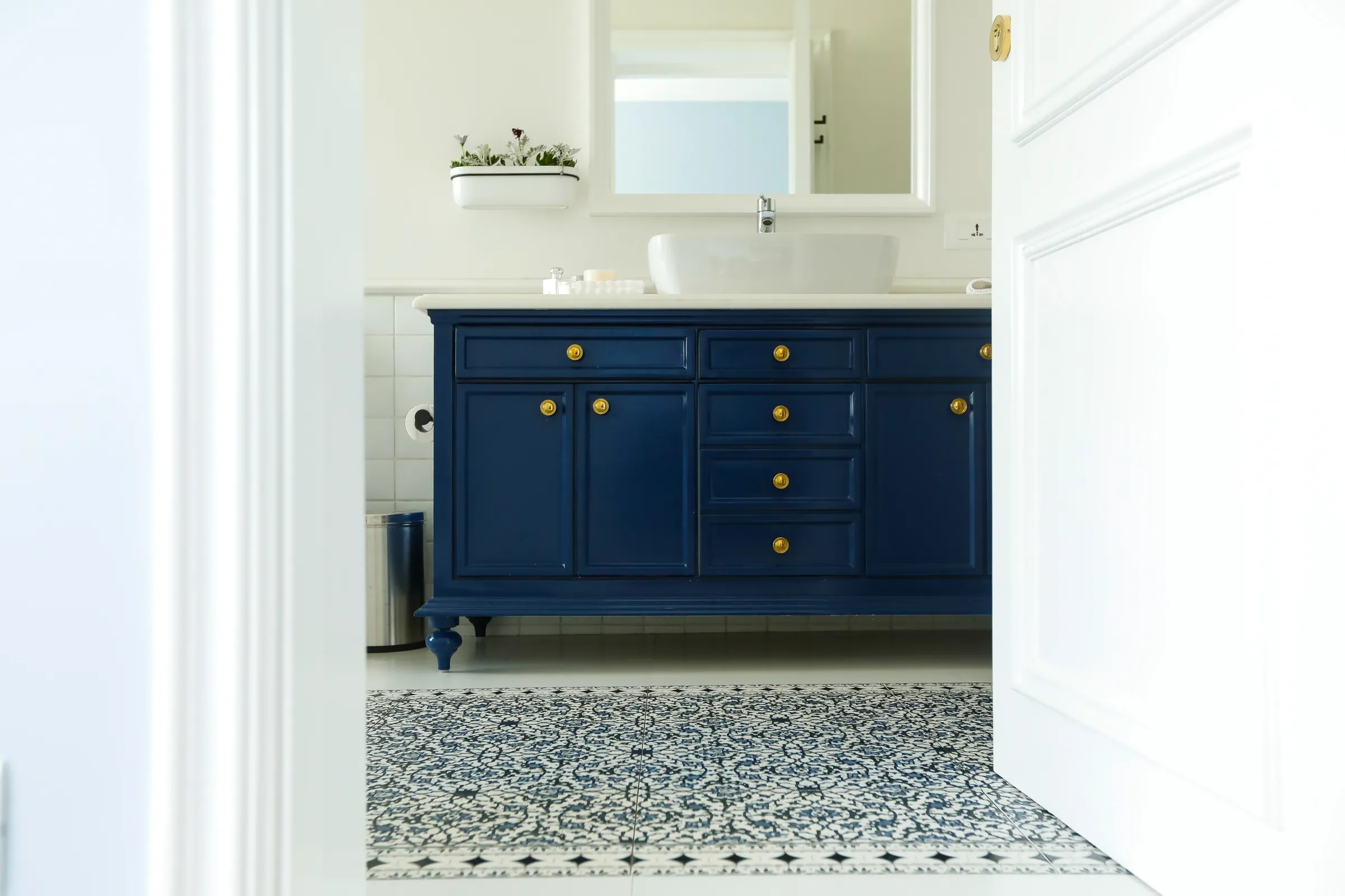 A powder room with a navy vanity and patterned tiles