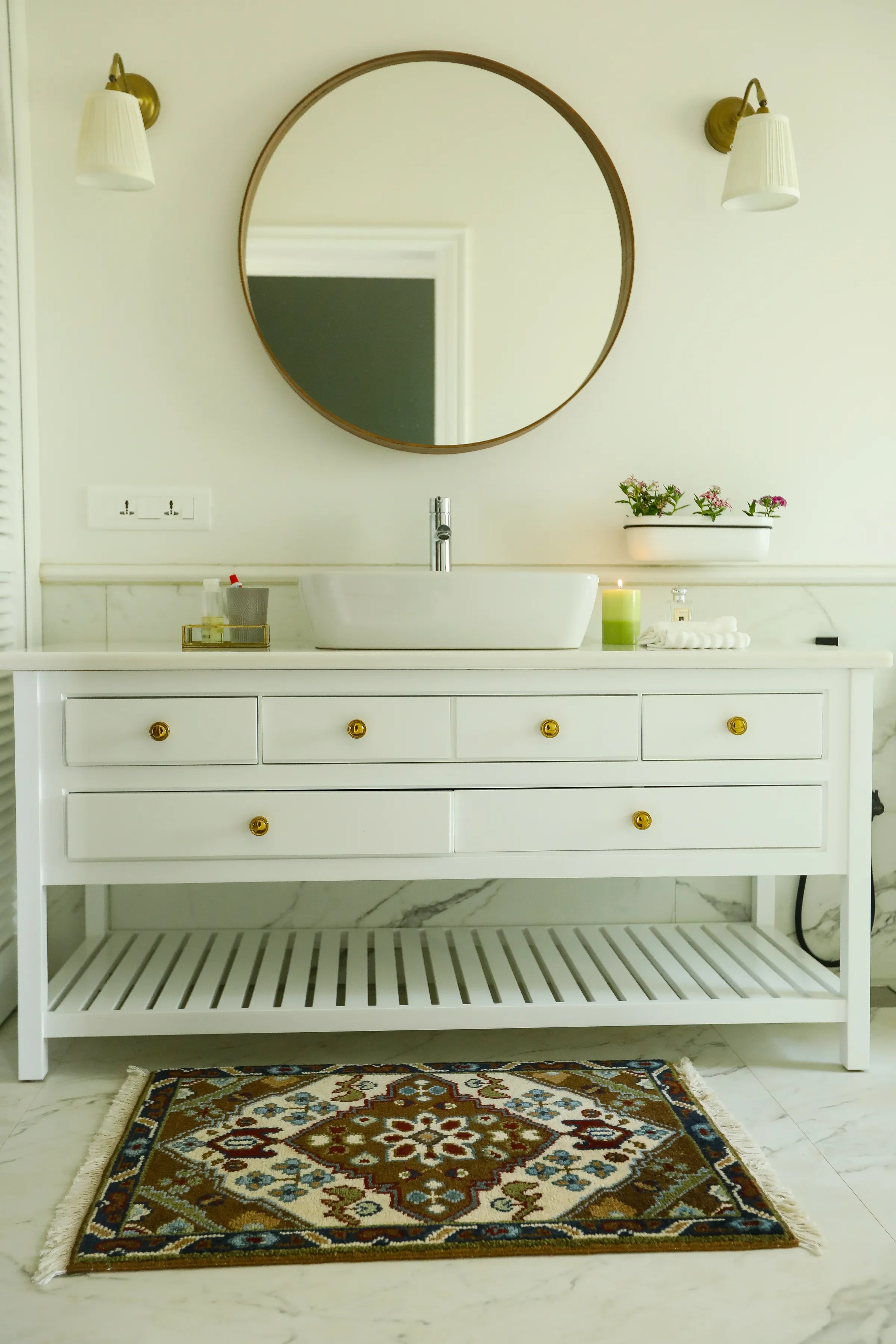 A white vanity under a round mirror