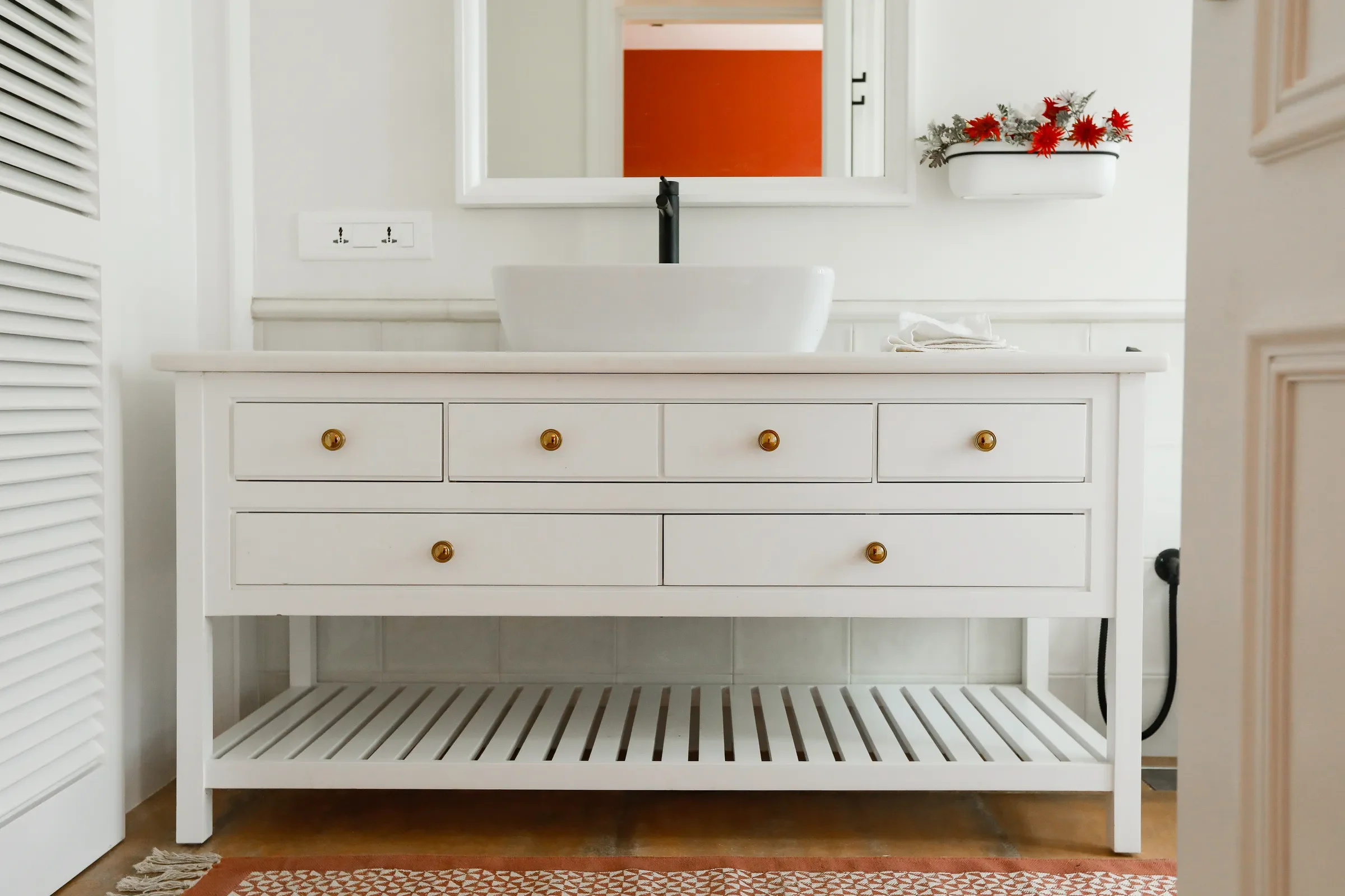 A white vanity with an orange splashback