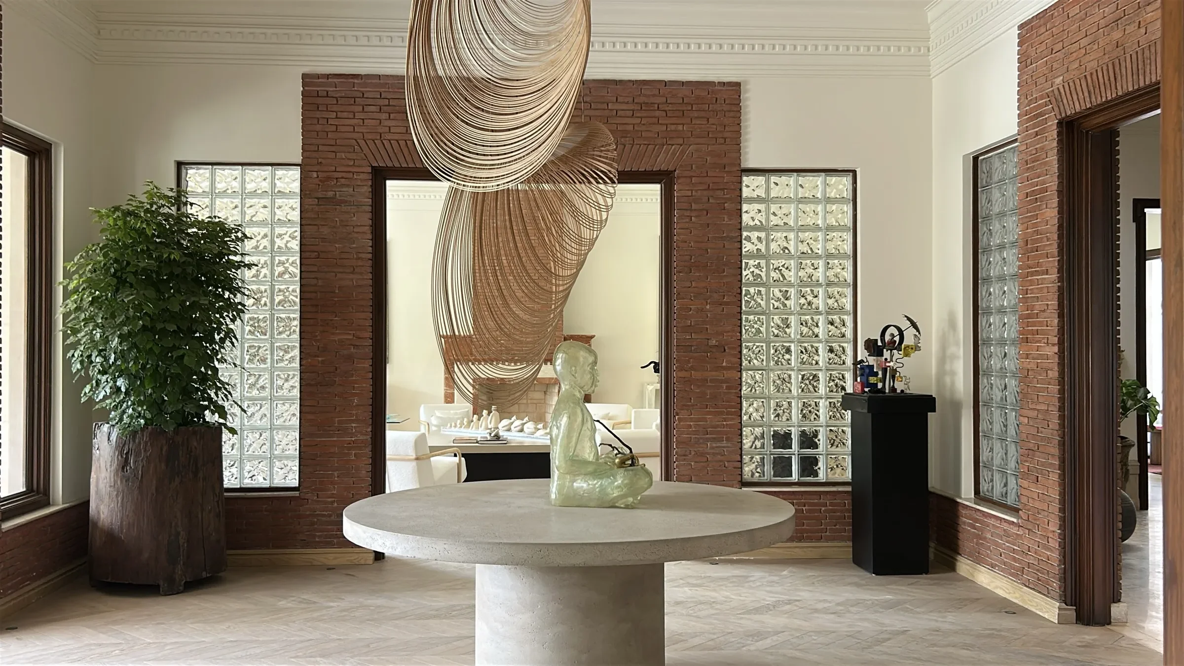 Brick-framed entrance hall with sculptural pendant and concrete table by Sonia Gehlot