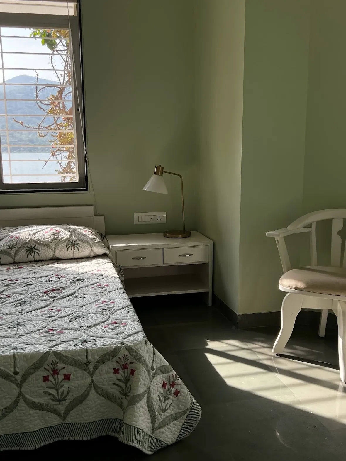 A green bedroom with the lake through the window at the Malkhed house