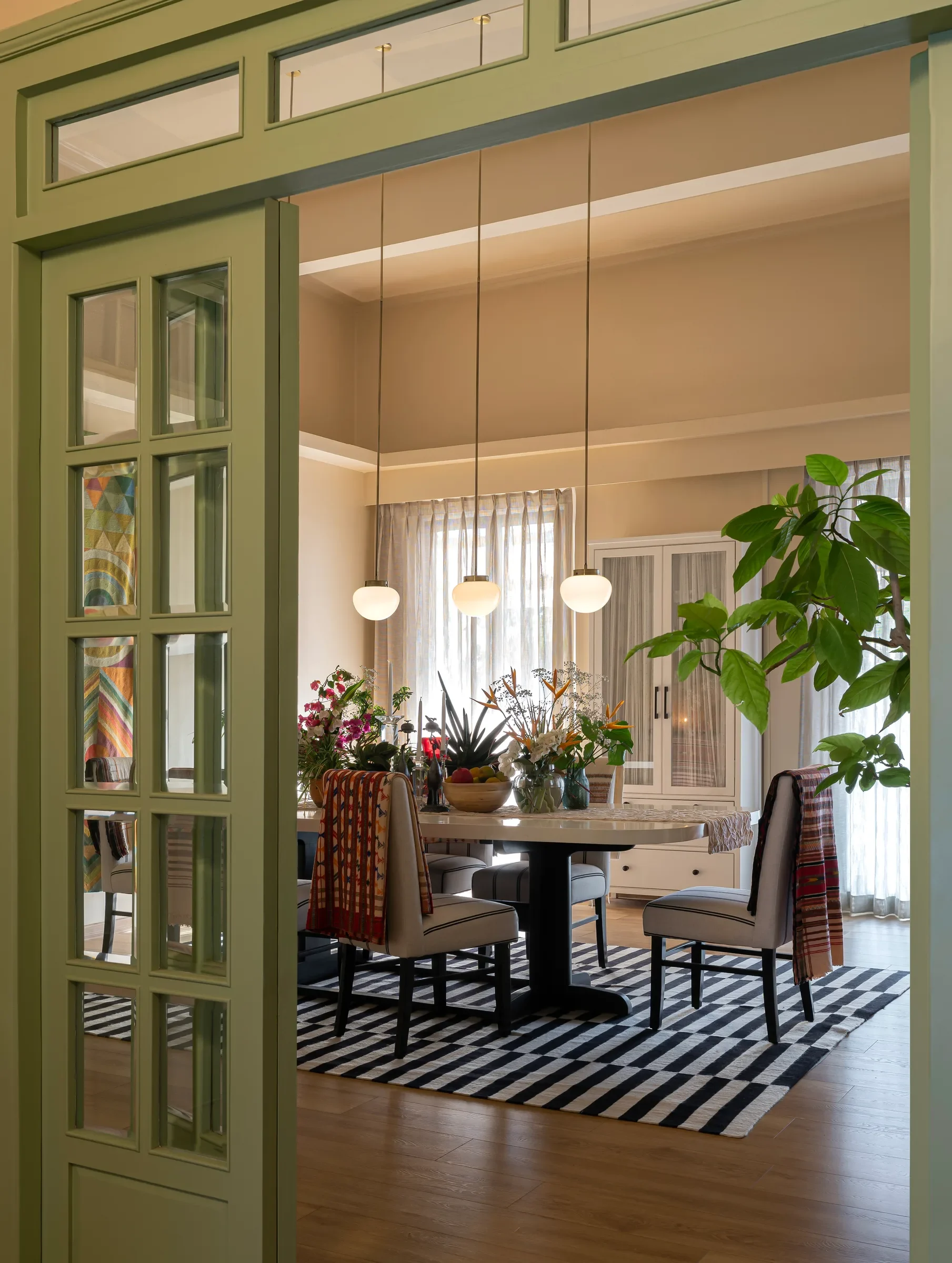 Green panelled doors opening onto the dining room at Tranquila, Mumbai, by Sonia Gehlot