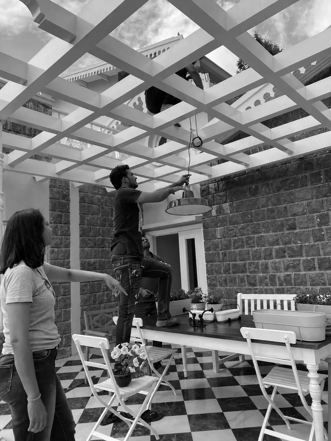 Hanging a pendant under the pergola on site, the studio looking on